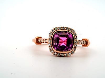 Purple sapphire ring set in a rose gold with a round brilliant diamond halo