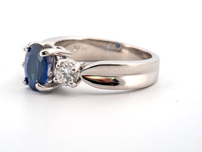 Blue sapphire 3 stone ring set with round diamonds in platinum with a fluted shank