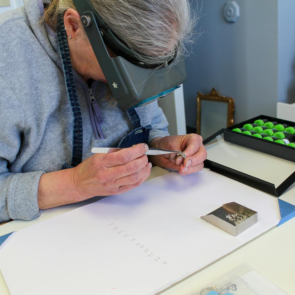 Marsha evaluating the fit of diamonds into a gold ring mounting